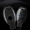 A pair of clear carbon fiber car key covers displayed against a dark background.