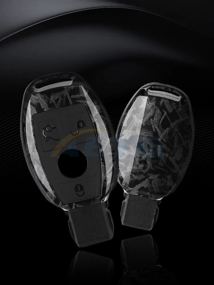 A pair of clear carbon fiber car key covers displayed against a dark background.