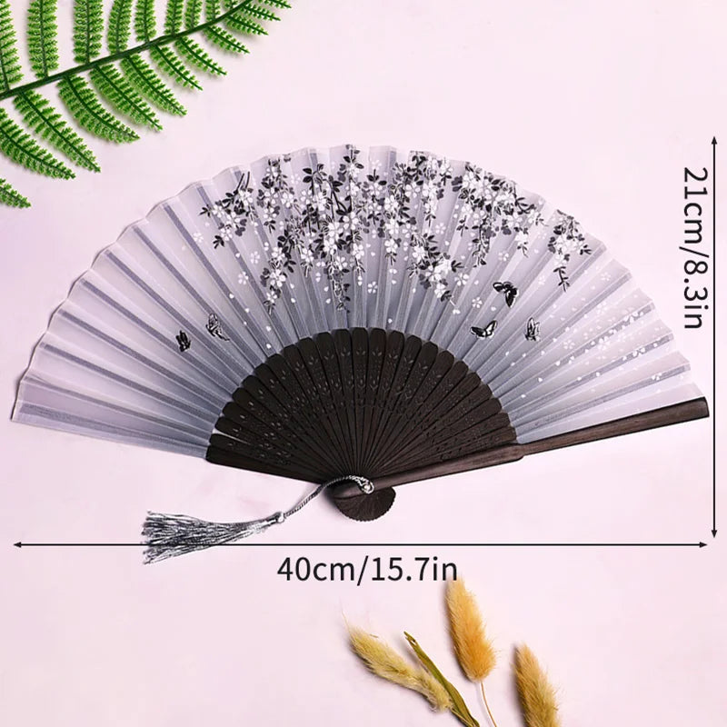 A vintage lace folding hand fan with a black handle and sheer gray paper, displayed on a white background.