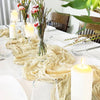 A rustic boho table setting featuring a semi-sheer gauze table runner, candles in glass holders, and greenery.