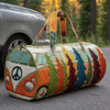 A quilted travel duffle bag featuring colorful, nature-inspired stitching and leather handles resting on an asphalt surface.