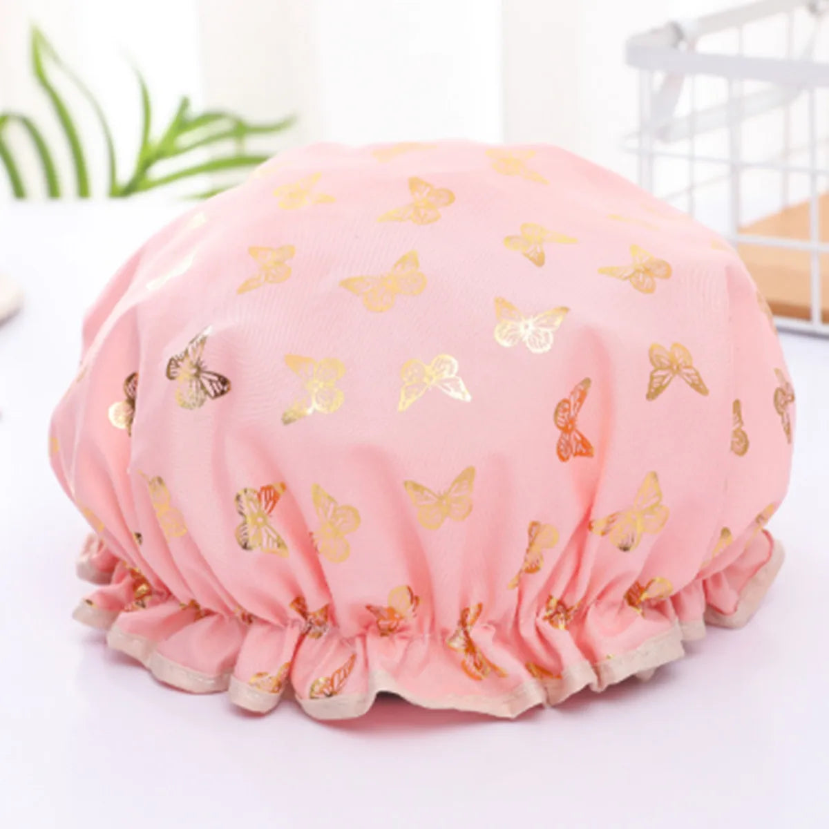 Pink reusable elastic shower cap decorated with gold butterfly patterns