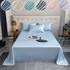 A bed dressed with light blue luxury bamboo flat sheets and pillows, featuring a modern headboard and decorative accents.