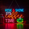 Neon sign spelling out Rise & Shine It's Coffee Time glowing brightly on a wooden surface.