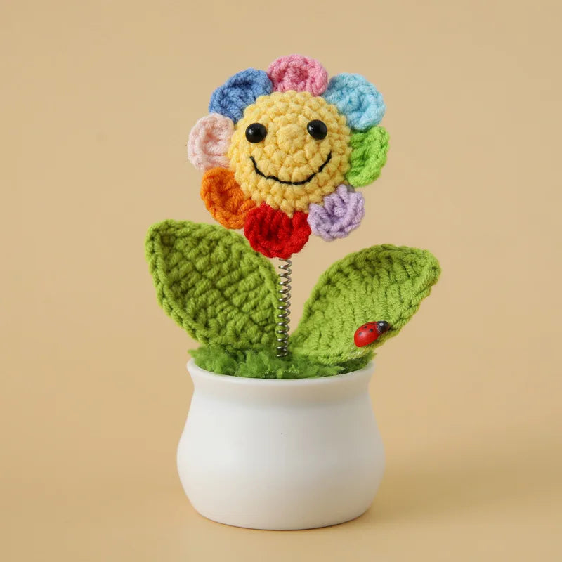 Handcrafted crochet sunflower with colorful petals growing in a white ceramic pot