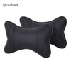 A pair of black leather knitted car neck pillows with a subtle dotted pattern.
