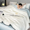 A cream colored ultra-soft comforter with embroidery featuring the words always and a butterfly design, draped on a bed.