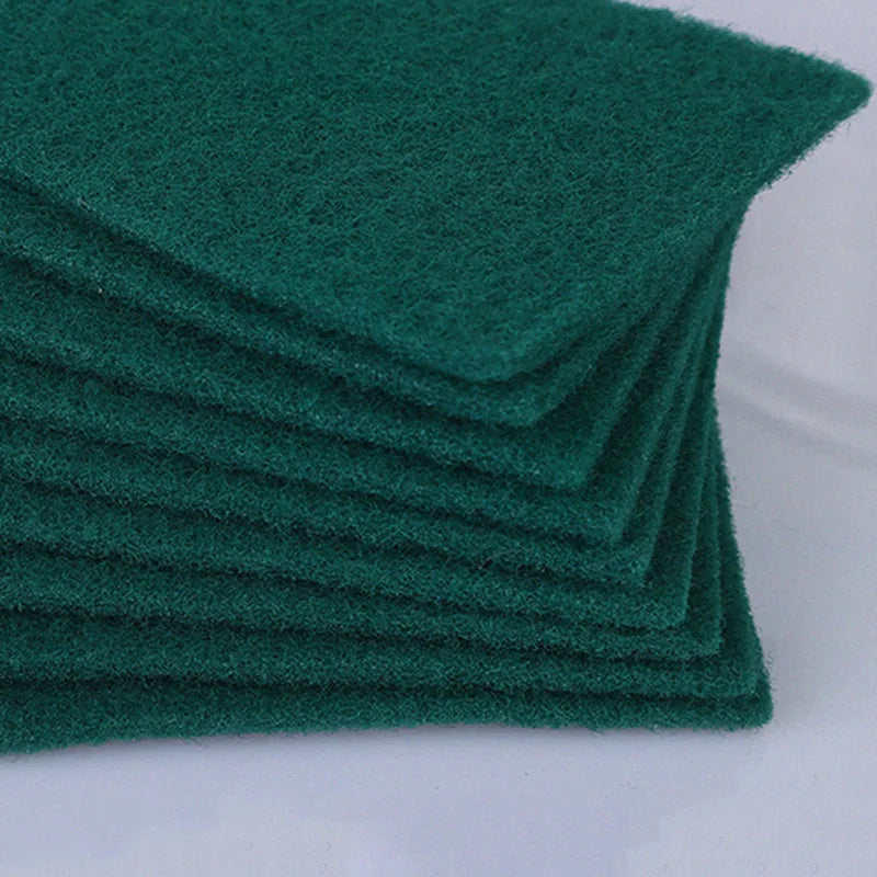 A stack of dark green microfiber kitchen scrub sponges for dishes and countertops.