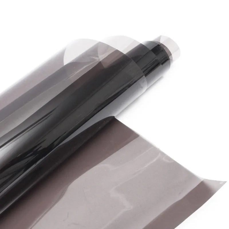 A roll of dark brown car window privacy film being peeled off a sheet.