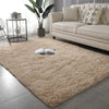 A fluffy beige Nordic furry accent rug placed on a gray floor in a modern living room setting.