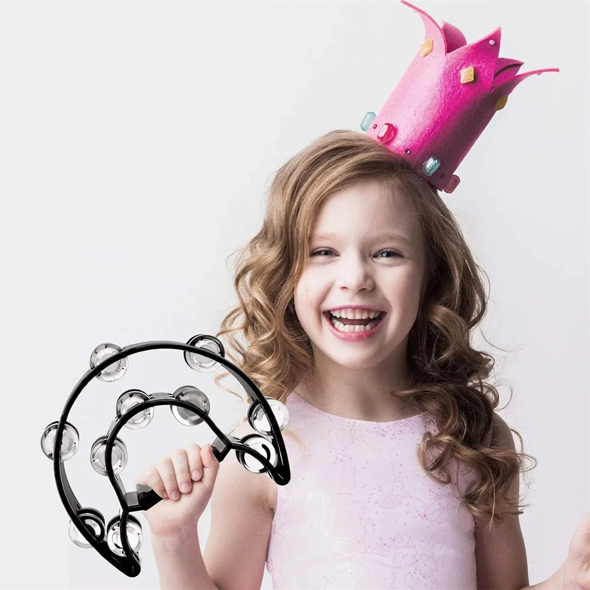 A smiling young girl holding a black half-moon tambourine with double row metal jingles.