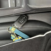 A black universal car seat gap filler and storage organizer with a key fob and various small accessories is shown in a vehicl