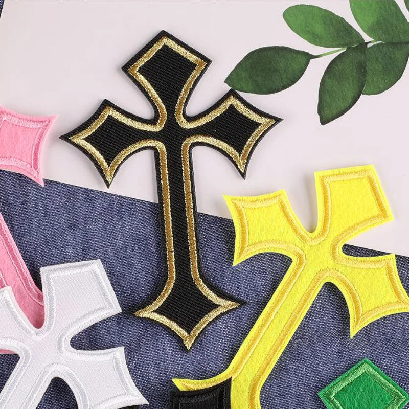 A collection of embroidered cross patches in black, gold, and yellow on a dark blue fabric background.
