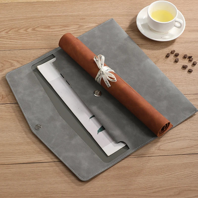 Un organisateur de documents en cuir marron avec une manchette blanche est posé sur un bloc gris à côté de grains de café et 