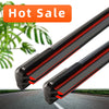 A close-up view of two black frameless wiper blades with dual red rubber edges on a car windshield.