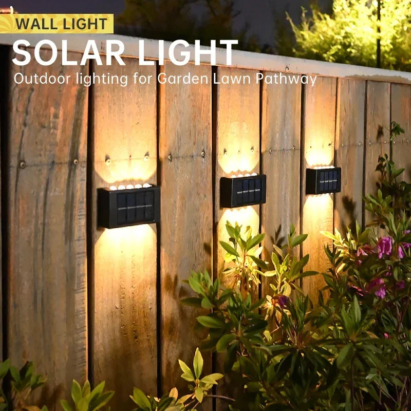 A row of solar light fixtures illuminating a wooden fence and surrounding greenery at night.