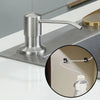 Stainless steel countertop liquid soap dispenser with an extension tube on a white surface.