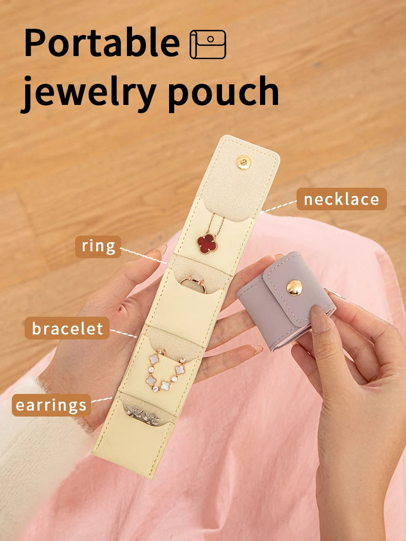 A hand holds a beige PU leather jewelry pouch displaying four compartments for storing necklaces, rings, bracelets, and earri