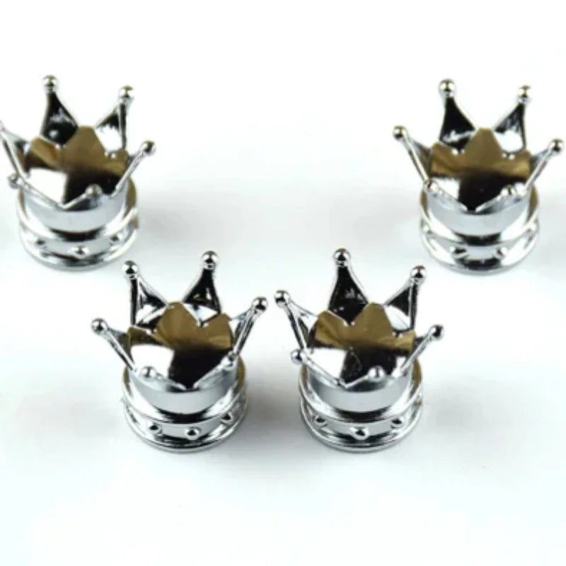 A set of four silver universal crown valve caps with decorative points.