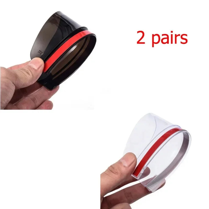 Two pairs of black carbon fiber car side mirror rain and sun visors shown being held by a hand.