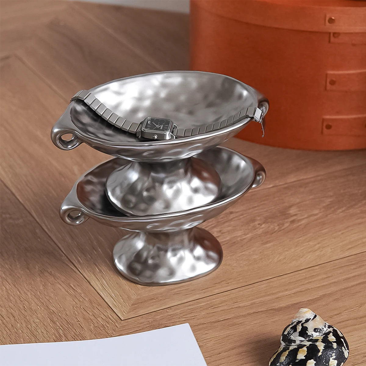 A silver vintage ceramic soap dish with an elevated stand resting on a wooden surface.