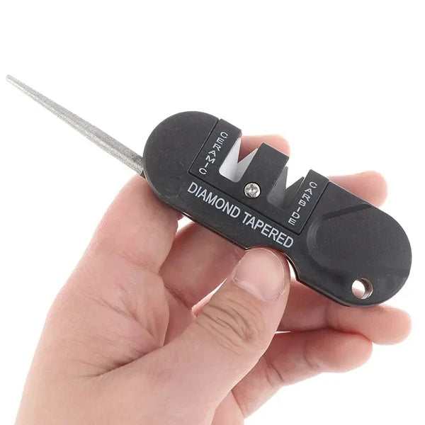 A hand holds a black diamond tapered knife sharpener with a metal blade and various sharpening stones.