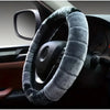 A cozy cartoon plush steering wheel cover wrapped in gray fur is shown on a car's interior dashboard.
