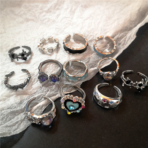 Eine Kollektion von Punk-Kristall-Herz-Schmetterlings-Geometrie-Ringen auf weißem Stoff.