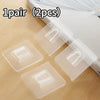 A pair of transparent, double-sided adhesive wall hooks are shown on a wooden surface.