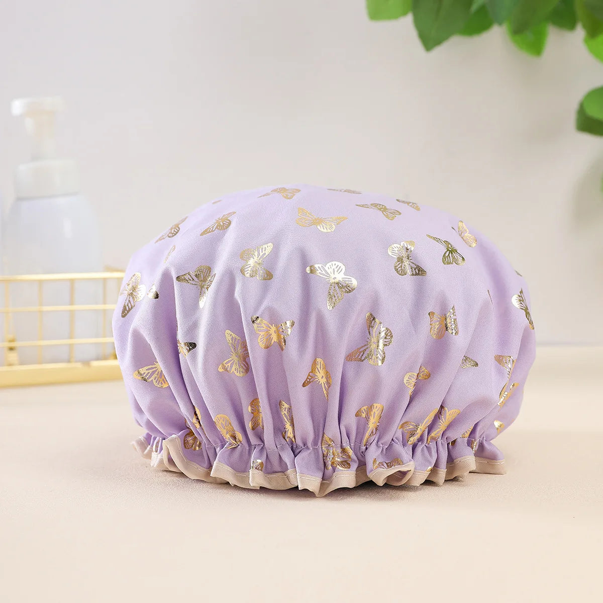 A lavender reusable elastic shower cap adorned with gold butterfly patterns.