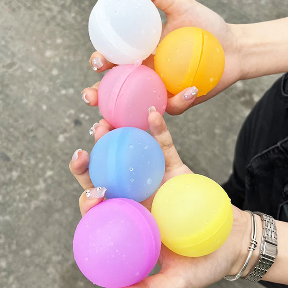 A hand holds a stack of colorful reusable splash water balloons in various shades including white, orange, pink, blue, and ye
