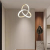 A modern pendant light with a gold-toned, circular ring design hangs in a minimalist interior space.
