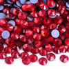 A close-up view of small, round red and purple rhinestones scattered on a white surface.