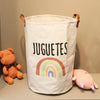 A white fabric storage basket with a rainbow design and the word JUGUETES printed on it.