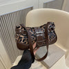 A brown leopard print PU leather shoulder bag is held in a hand against a light background.