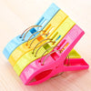 A set of heavy-duty plastic laundry clips in blue, yellow, and pink stacked on a wooden surface.