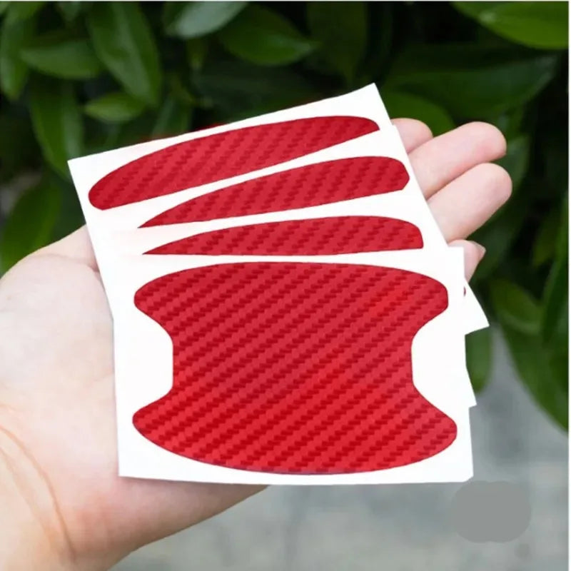 A hand holds a white card displaying three red carbon fiber patterns, representing door handle protector film.