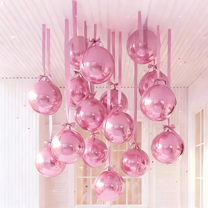 A collection of ten metallic pink round foil balloons hanging from a white ceiling.