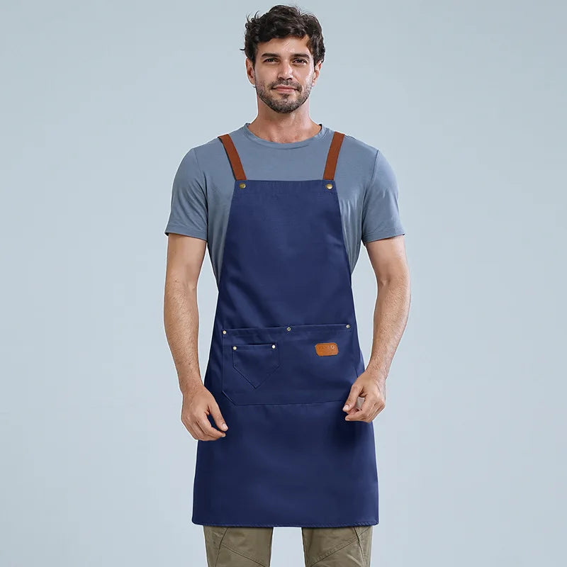 A man wearing a navy blue waterproof adjustable kitchen apron over a gray t-shirt.