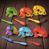 A collection of handcrafted wooden frog guiro rasp percussion instruments in various colors and shapes.