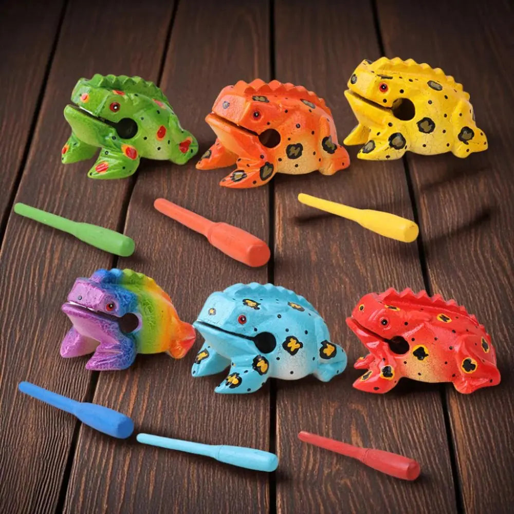 A collection of handcrafted wooden frog guiro rasp percussion instruments in various colors and shapes.