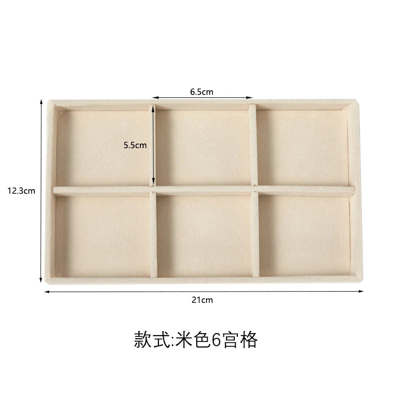 A rectangular beige velvet jewelry organizer tray with six detachable compartments.
