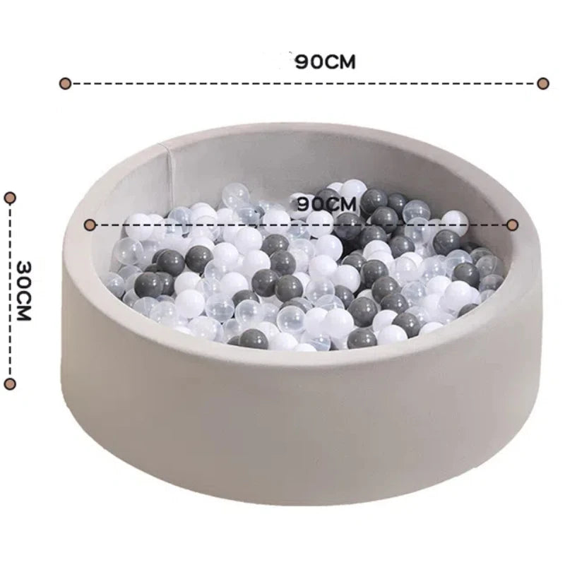 A round, light-colored ball pit with a rim, filled with mixed white and gray plastic balls.