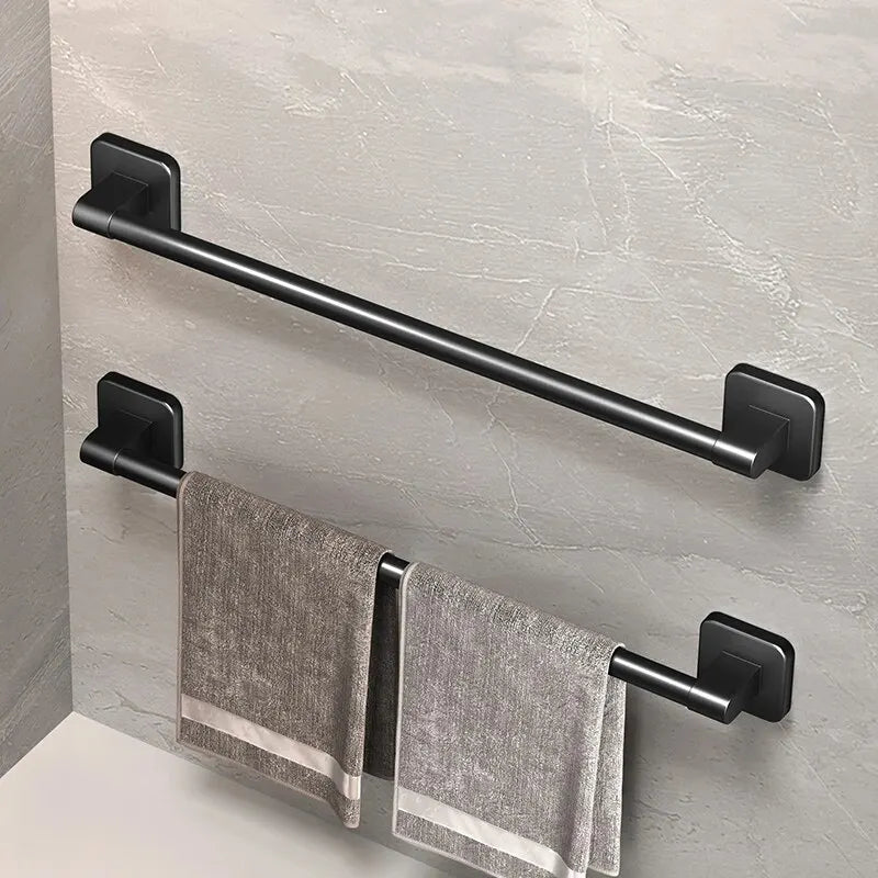 A black wall-mounted towel rack with a horizontal bar and two hanging gray towels mounted on a light gray wall.