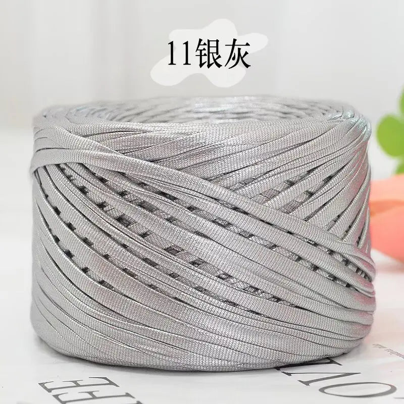 A spool of silver metallic flat ribbon yarn for crochet and knitting.