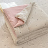A folded lightweight summer quilt featuring a striped pattern and small heart motifs on a neutral fabric.