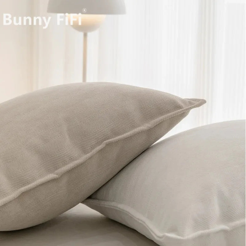 A close-up of two beige soft chenille throw pillow covers on a white surface.