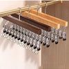 A wooden clip hanger with twelve metal clips is displayed on a light wood background.