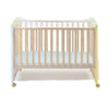 A wooden baby crib with a sheer mosquito net draped over the top.