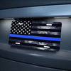 A thin blue line American flag metal sign displayed on a gray surface.